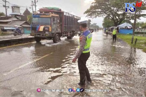 ATUR LALIN : Petugas Satlantas mengatur kendaraan di jalan Pantura Onggorawe Sayung yang sedikit masih tergenang air. (Wahibpribadi/jawapos radar semarang)